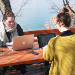 Twee studenten buiten aan het werk met laptop aan picknicktafel, uitzicht over Meer van Ohrid