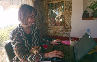 Student Erna achter laptop voor een raam in muur van grove stenen