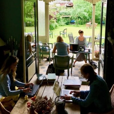 Focusdag mensen werken gefocust achter hun laptop in een huiskamer-setting met uitzicht op veranda en tuin