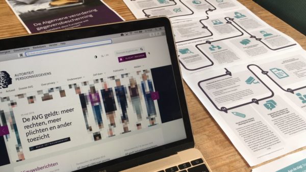 Autoriteit Persoonsgevens website over AVG op beeldscherm en folders op tafel