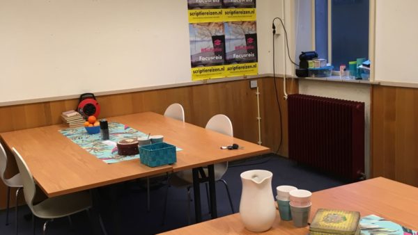 huiselijk aangeklede ruimte met tafels en stoelen, fruit en koekblikken op de tafels