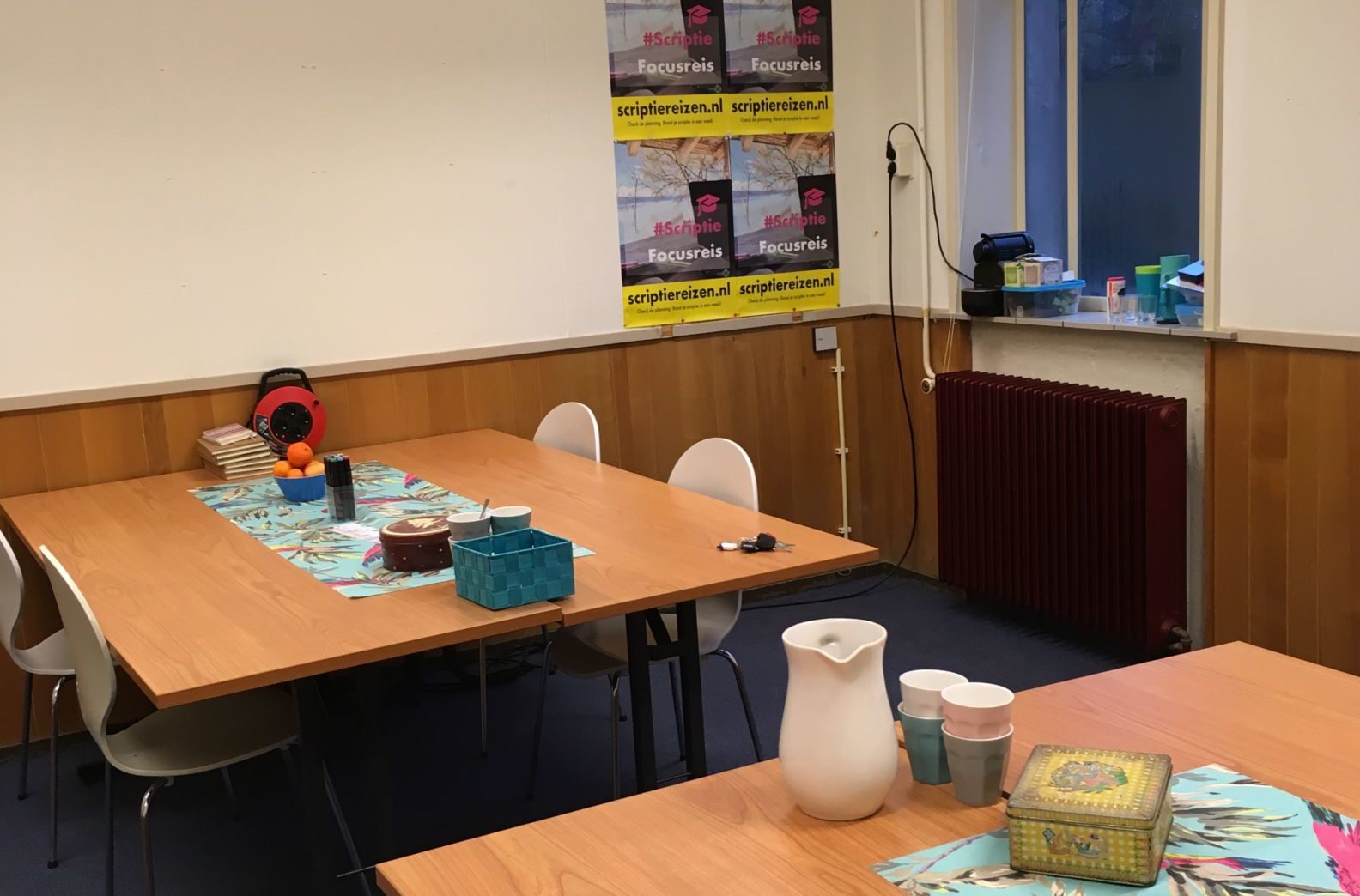 huiselijk aangeklede ruimte met tafels en stoelen, fruit en koekblikken op de tafels