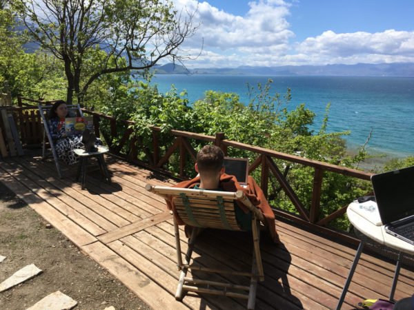 studenten werken buiten aan hun scriptie met zicht op meer van Ohrid