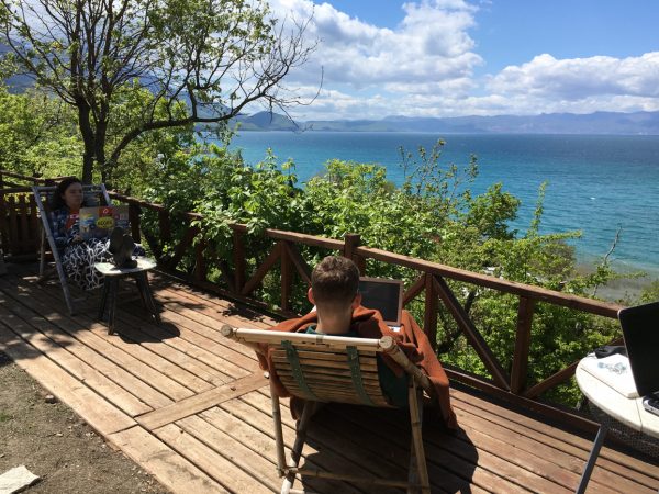 studenten werken buiten aan hun scriptie met zicht op meer van Ohrid